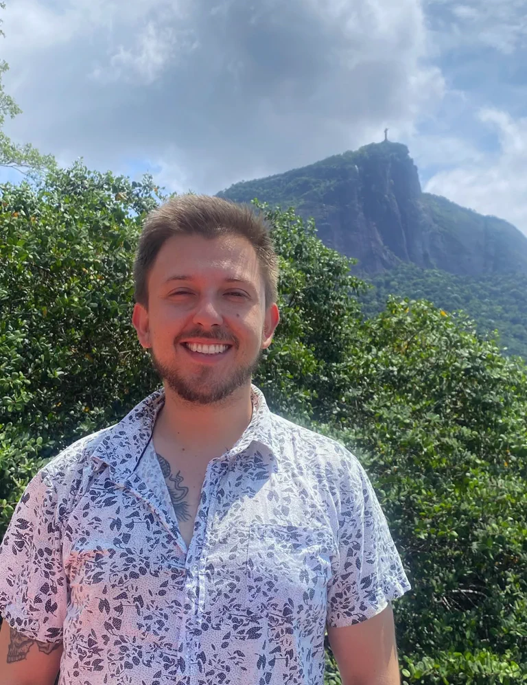 Arthur Fischer sorrindo ao ar livre, com o Cristo Redentor ao fundo.